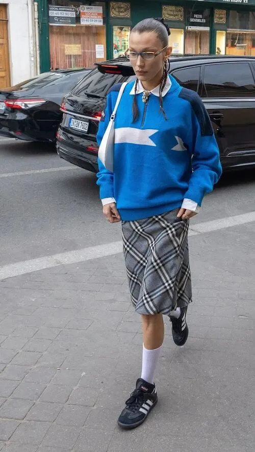 Bella Hadid wearing Adidas Samba sneakers, retro harf-zip sweatshirt, and midi tan tan tan skirt