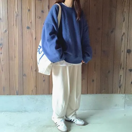 a woman wearing white Adidas Samba sneakers, blue oversized sweater, white wide leg pants