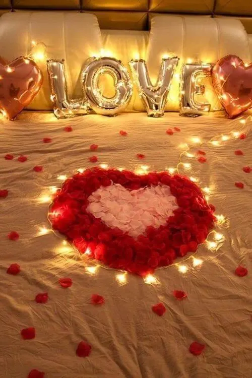 Valentines Day room decoration ideas for the bed with lights, roses, and balloons