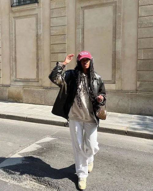 a black woman wearing a pink baseball cap, and sweatshirt set