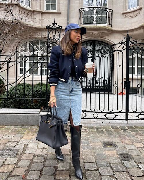 a woman wearing baseball hat, short jacket, and denim midi skirt