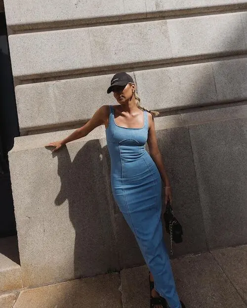 a woman wearing a baseball cap and maxi denim dress