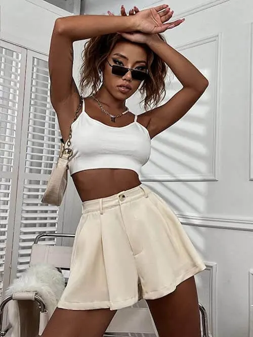 a woman wearing a white crop tank top and beige wide leg shorts