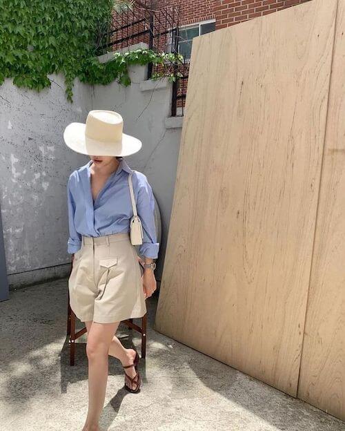 a woman wearing a hat, blue shirt, beige shorts