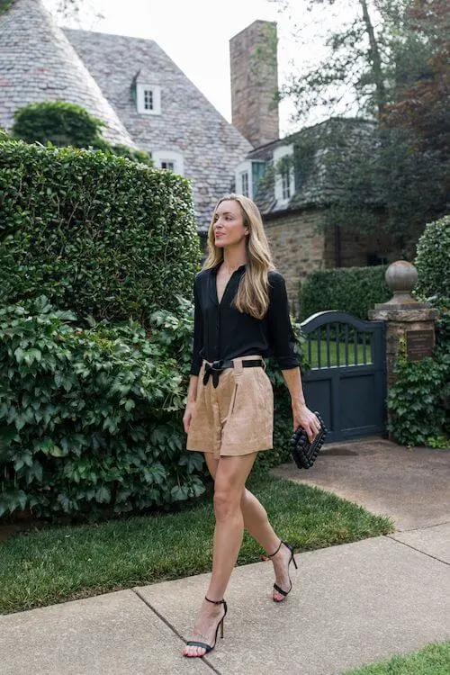 a woman wearing a black blouse and beige shorts