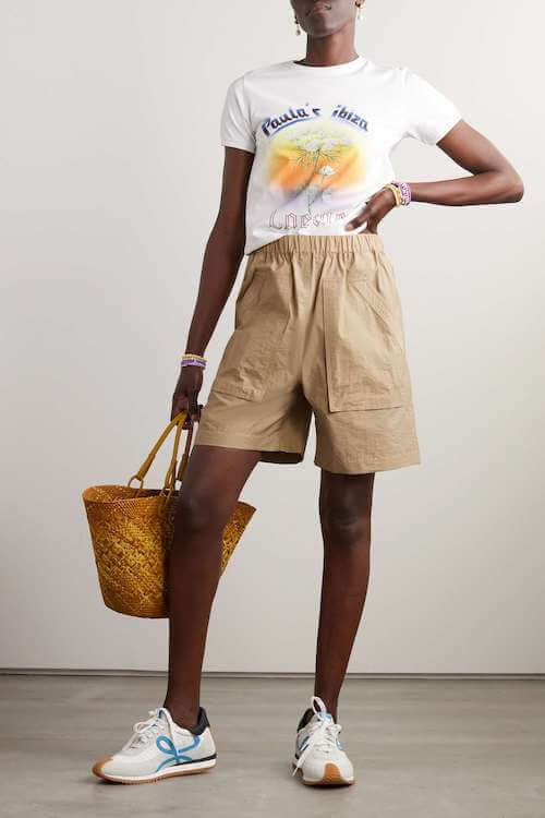 a black woman wearing graphic tee, beige shorts, and white sneakers