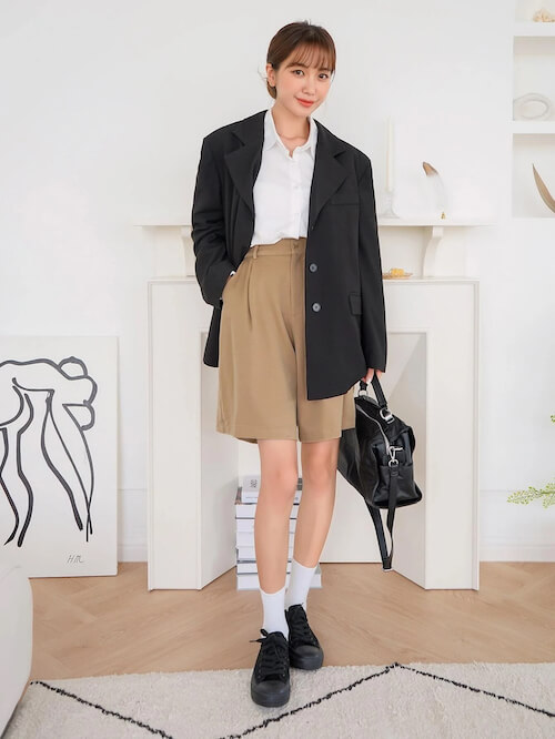 a Korean woman wearing beige shorts, black blazer and white shirt