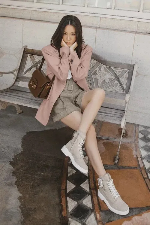 a woman wearing dusty pink blazer, beige shorts, and sneakers