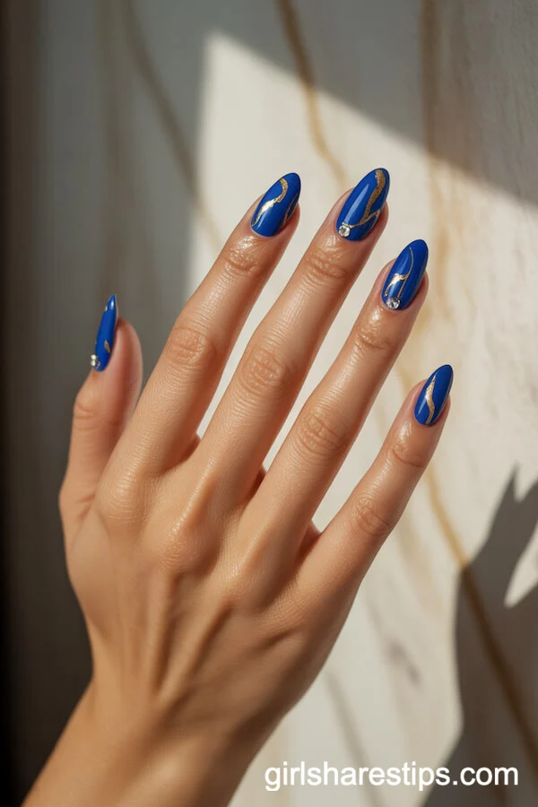Royal Blue Almond Nails with Gold Leaf and Rhinestone Accents