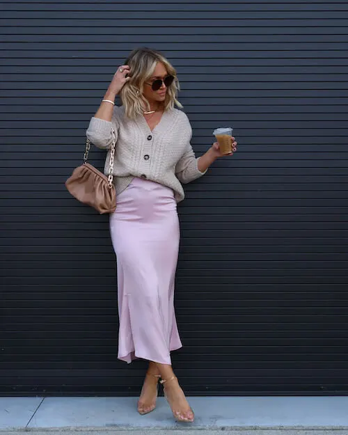 a woman wearing a light gray cardigan and light purple satin midi skirt