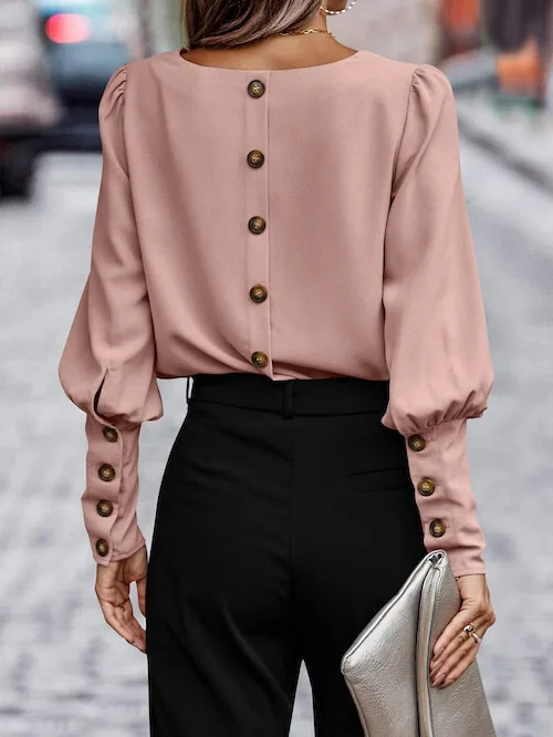a woman wearing a dusty pink blouse and black pants