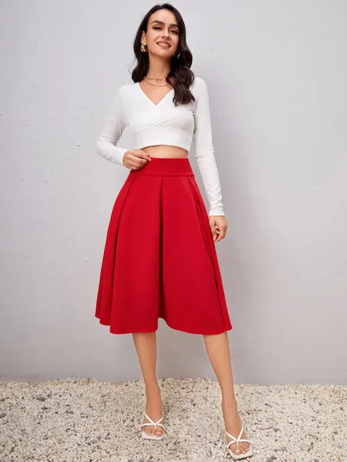 a woman wearing long sleeve white top and a red a-line skirt