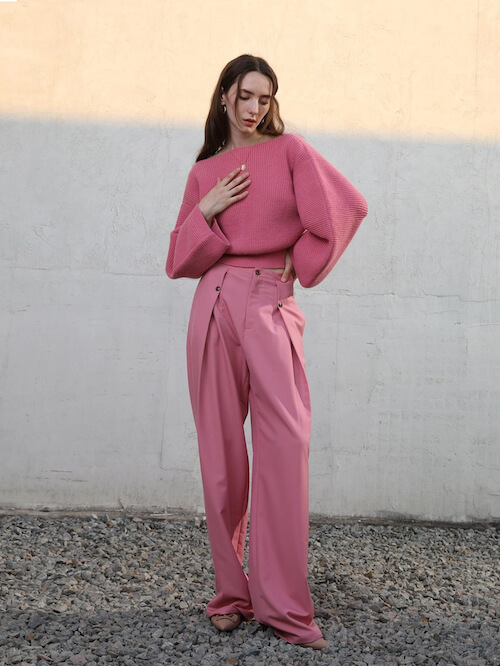 a woman wearing a pink sweater and a pair of pink wide leg pants