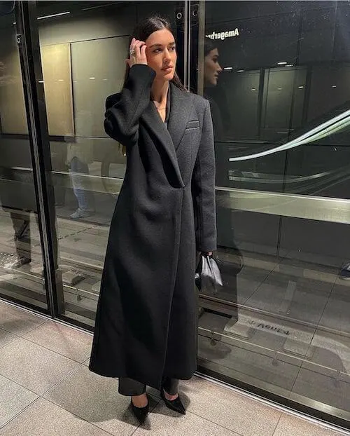 a woman wearing a long black coat in winter