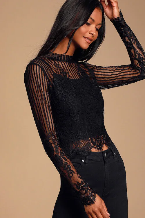 a black woman wearing a black lace mesh top and black jeans