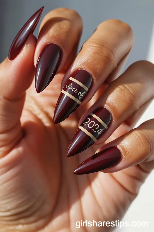 Deep Burgundy Stiletto Nails With Gold Accents and &ldquo;Class of 2024&rdquo; Script