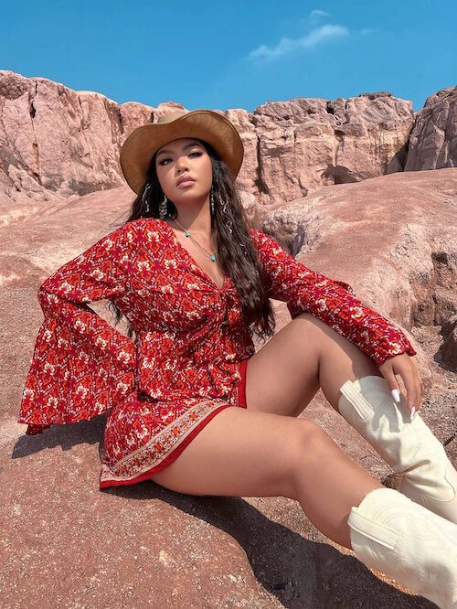 a woman wearing a cute red dress, a pair of cowgirl boots, and a straw hat