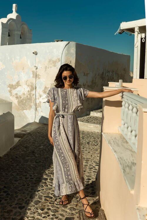 woman wearing a printed maxi dress, strappy sandals, and sun glasses in her desert trip
