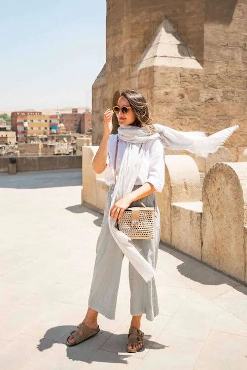 woman wearing linen scarf, white blouse, wide leg pants and sandals