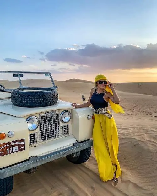 a stylish woman standing in the desert, wearing bright yellow head scarf and yellow pants