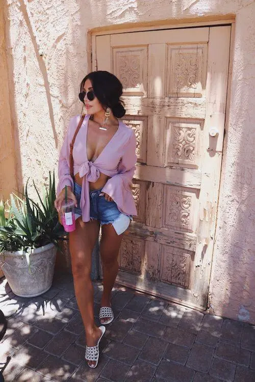 woman wearing a pink blouse, denim shorts and white slides