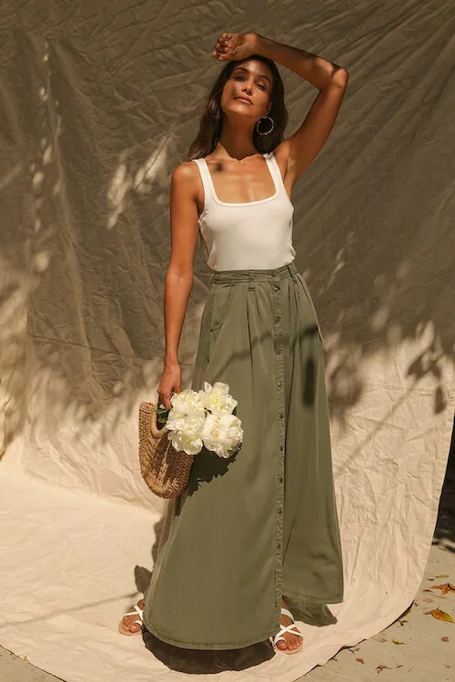 a woman wearing a white tank top and a flowy skirt