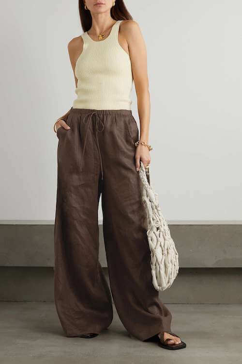 a woman wearing a simple tank top and a pair of brown baggy linen pants