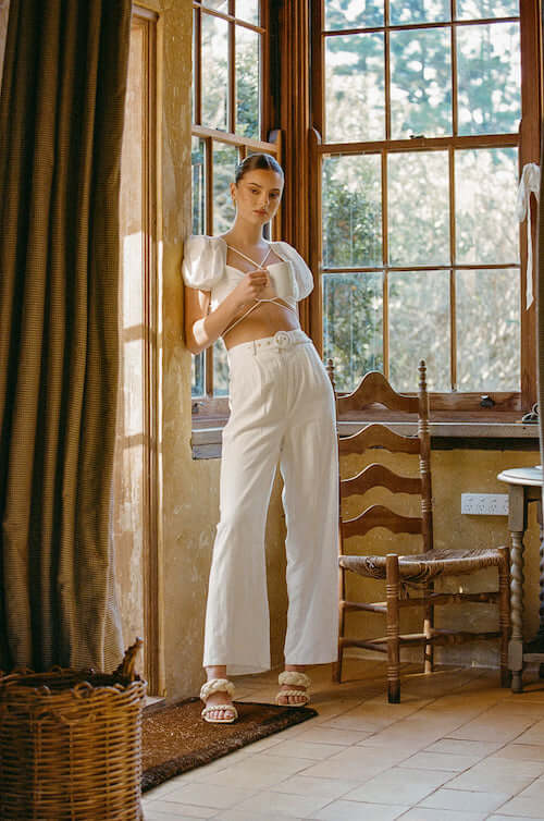 a woman wearing a white crop top and high rise linen pants