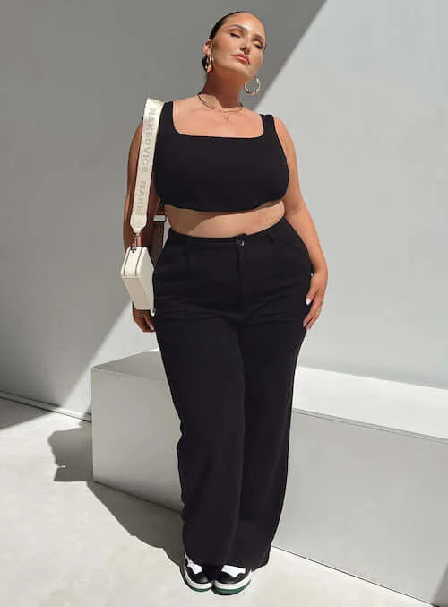 a plus size woman wearing a simple black top and a pair of black linen pants