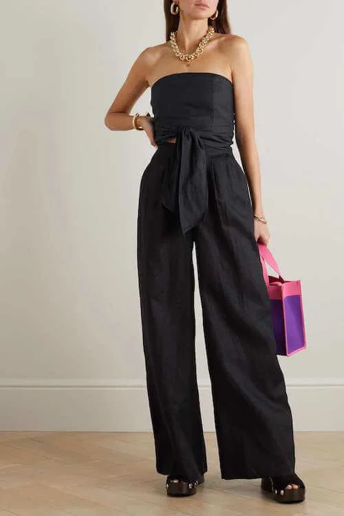 a woman wearing a black cold shoulder top and a pair of black linen pants