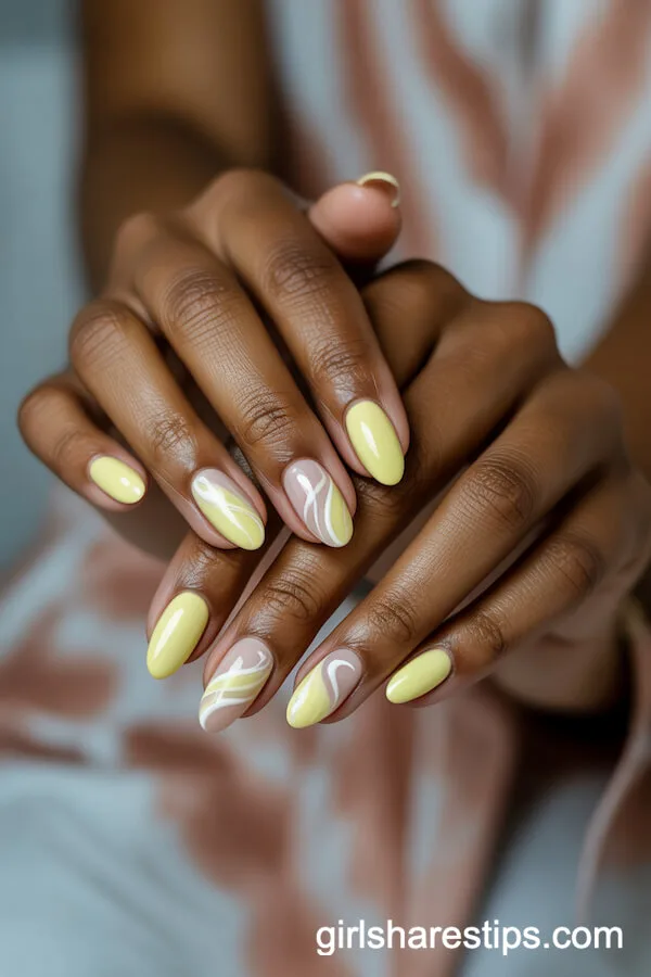 Almond Nails with Pastel Yellow Base and Artistic White Swirls