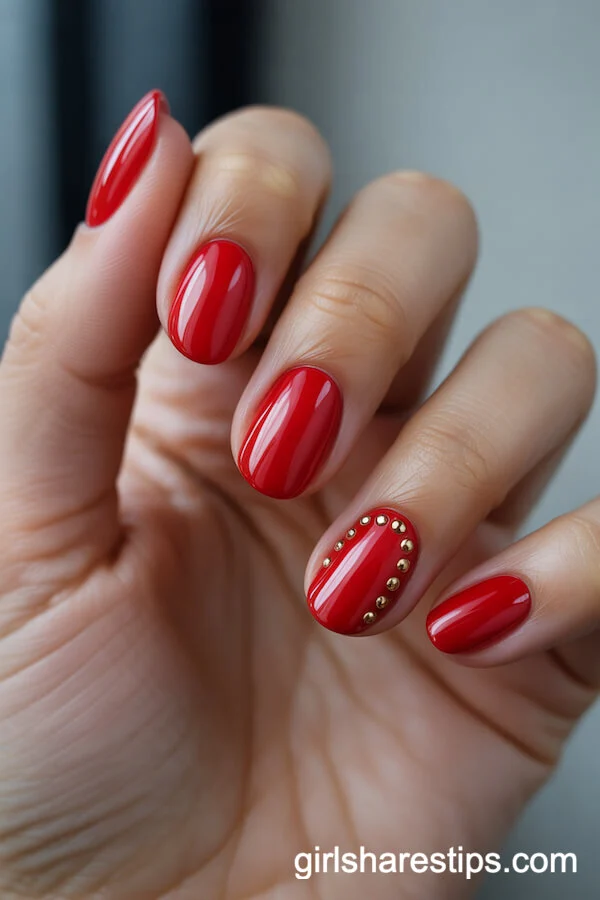 Glossy Red Round Nails with Gold Stud Embellishments
