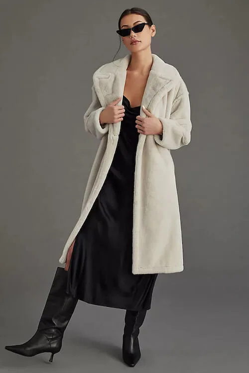 white shearling coat, a long black dress, and black boots