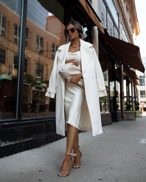 a beautiful woman wearing a slip dress an a white long coat