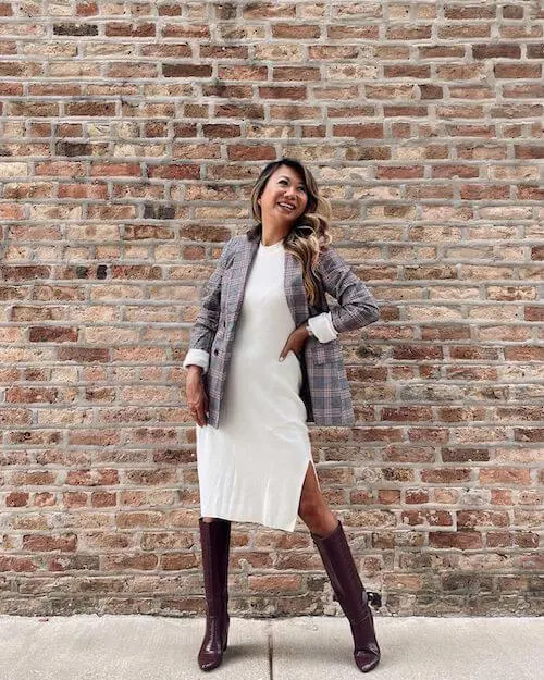 an asian woman wearing a white dress and a chic blazer with boots