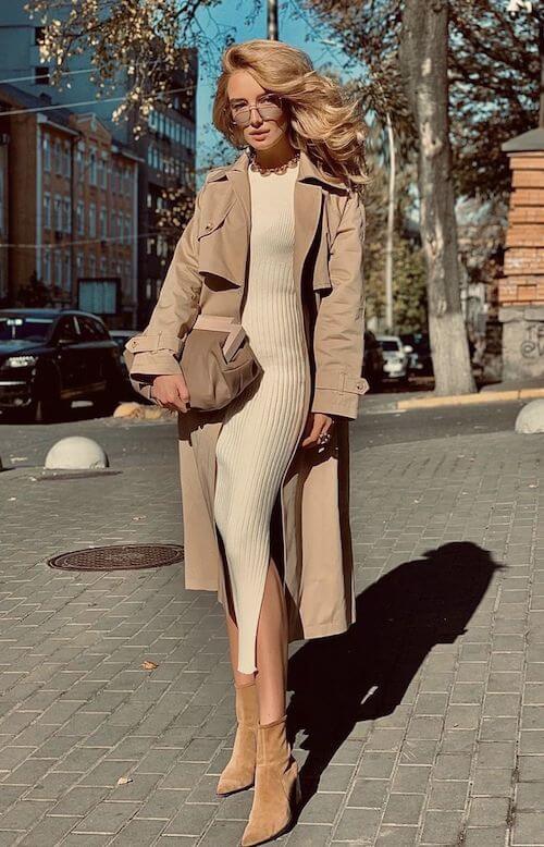 a woman wearing a maxi beige knit dress and a camel trench coat