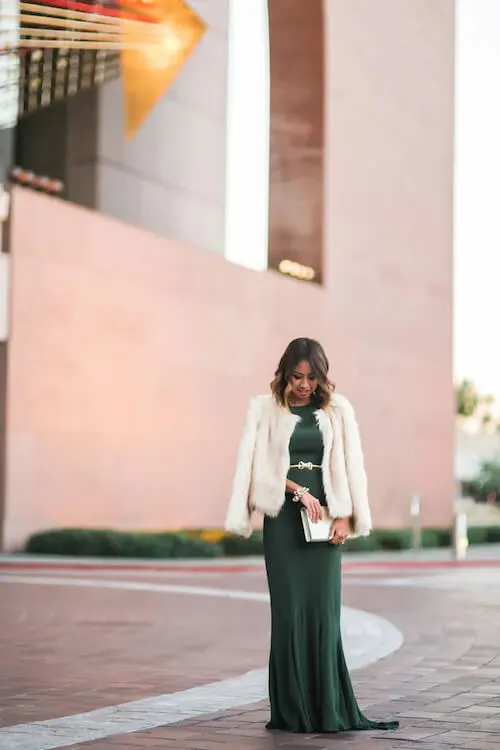 a asian woman wearing a cream faux fur coat, a green formal gown, for a formal winter event