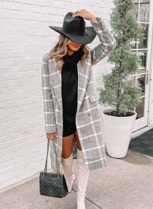 a woman living in Nashville wearing long plaid coat, black turtleneck knit dress, a pair of white boots, and a hat