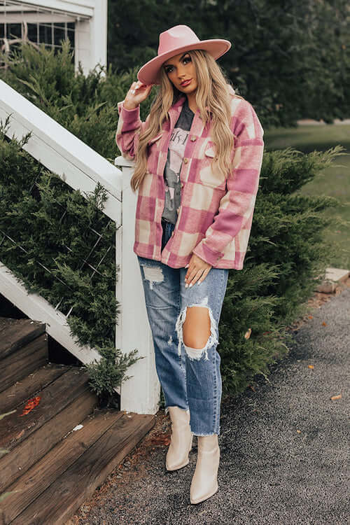 a woman wearing pink plaid shacket, graphic tee, denim jeans, white ankle boots, and a pink cowgirl inspired hat
