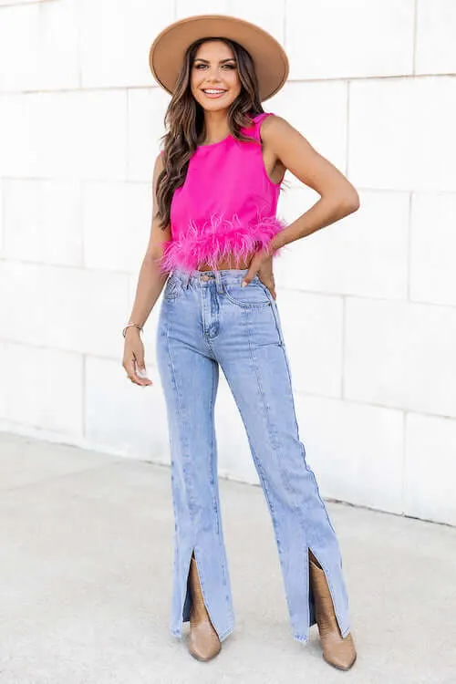 a woman visiting Nashville city wearing hot pink crop top, a pair of flare jeans, and tan cowboy boots
