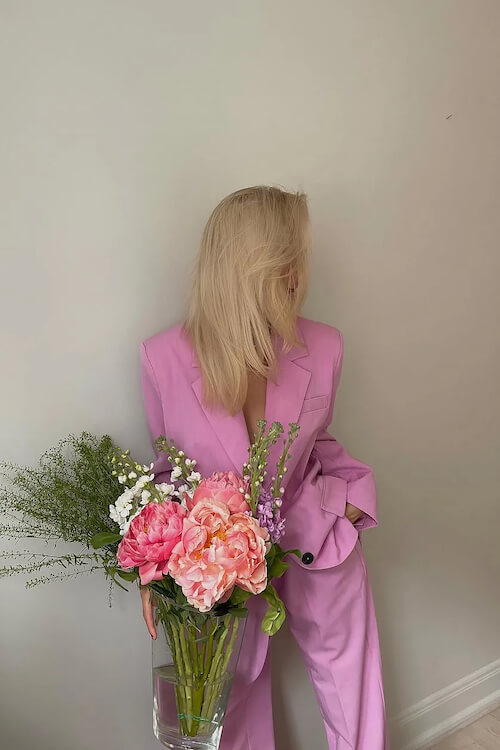 a woman wearing a light pink blazer suit